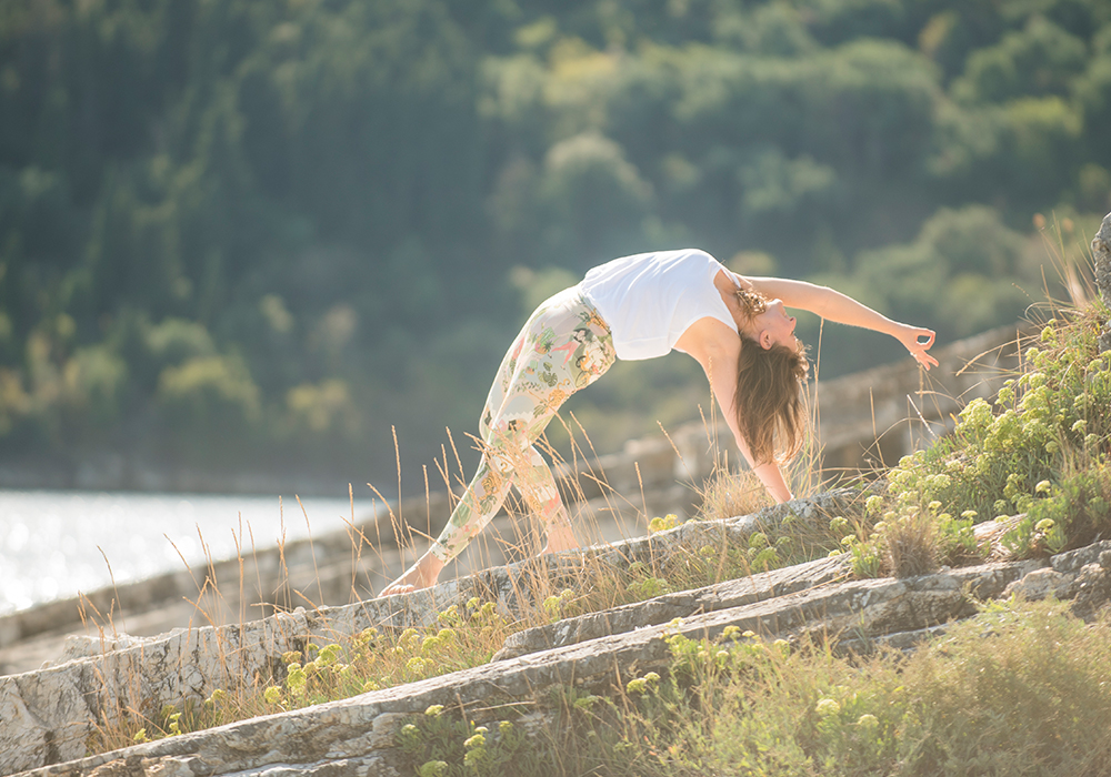 Frau übt Yoga auf einer Klippe Wildthing