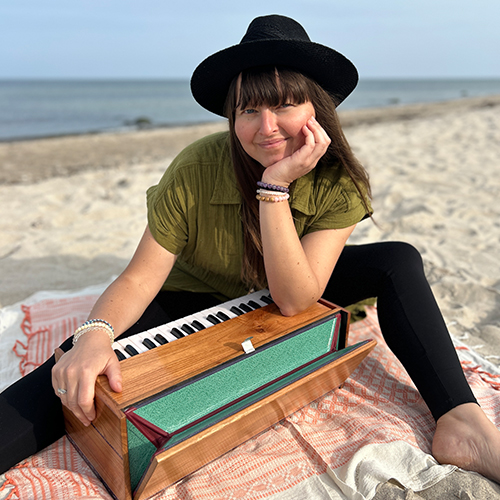 Frau am Strand mit einem Harmonium Musikinstrument