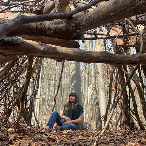 Frau sitzt in der Natur an einem Baum